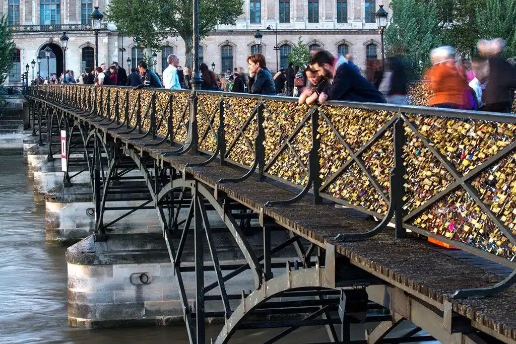A view of people standing at the Paris love locks near the bridge