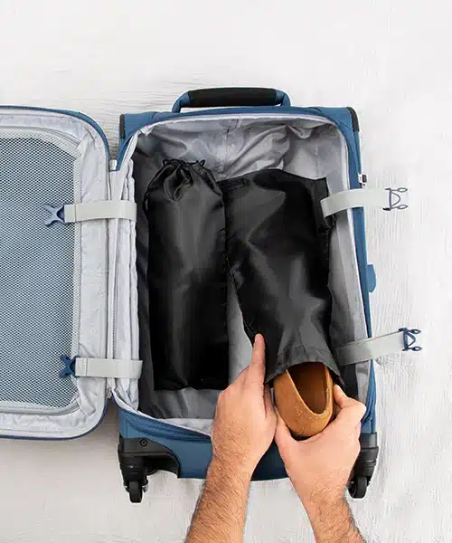 a person is packing suit shoes in a suit case