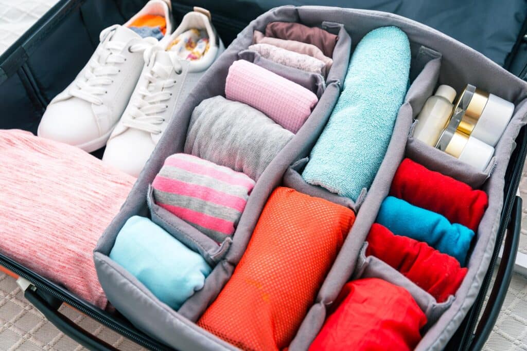a view of a suit case showing shoes and clothes in different compartments