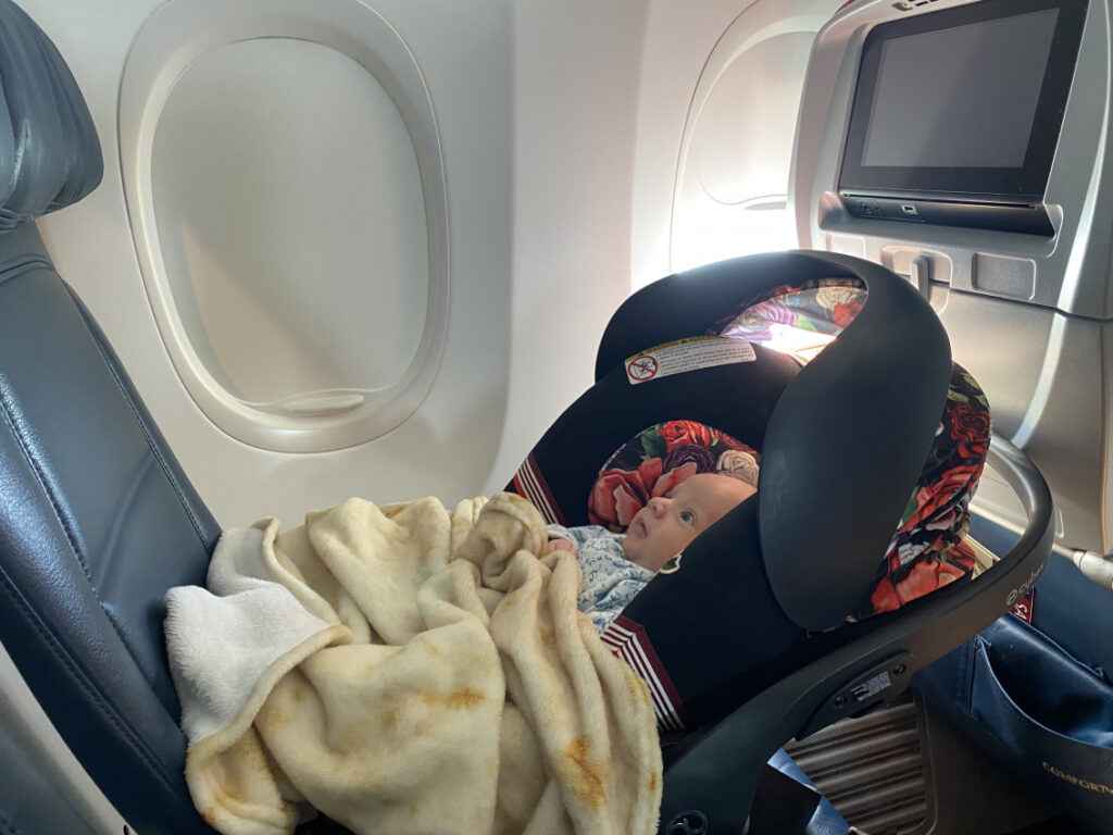 a baby lying in car seat in the airplane