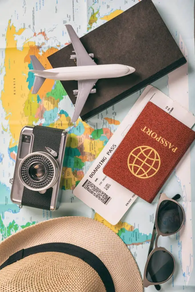 a camera hat passport and mini toy plane on a map