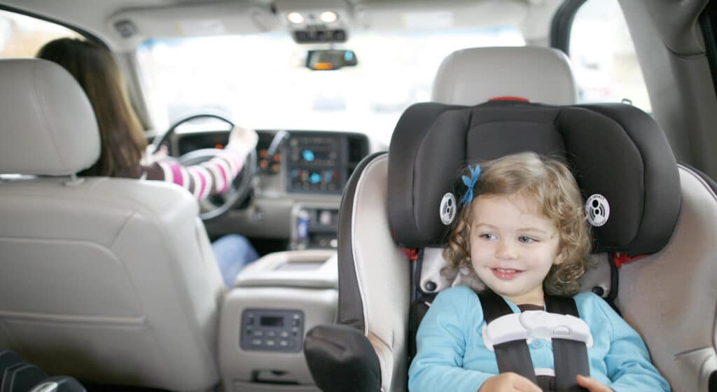 a girl is sitting in a rear facing car seat