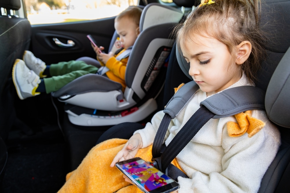 Cute Siblings Sitting In Baby Booster Car Seats And Using