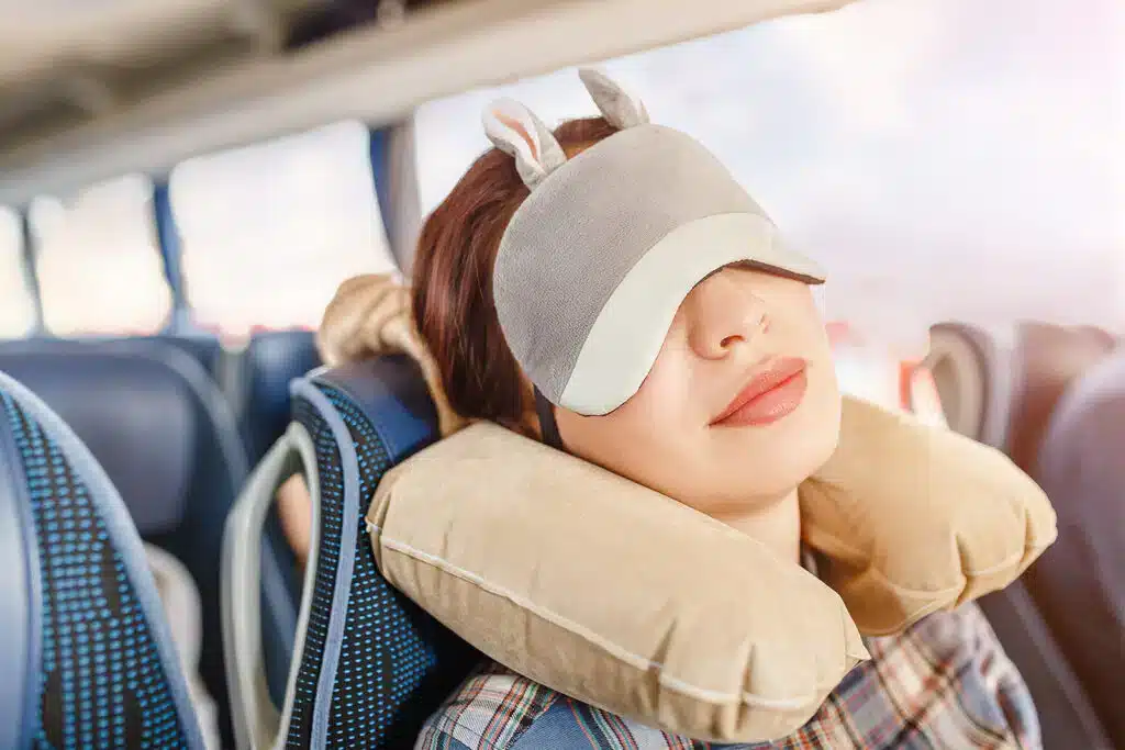 a lady wearing eye cover and using ravel pillow while travelling jpeg